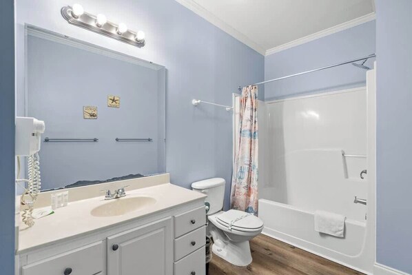 A bathroom with a vanity, toilet, and bathtub.