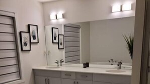 Une salle de bain moderne avec une grande baignoire, un meuble-lavabo à deux vasques et un grand miroir.