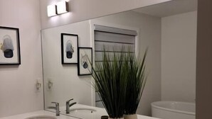 Une salle de bain moderne avec deux lavabos, un grand miroir et une plante en pot.