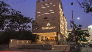 Un edificio moderno con un letrero que dice 'KRISHNA INN' en la entrada.