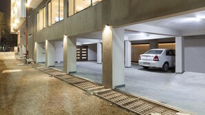 Un estacionamiento de varios niveles con pilares de concreto y un coche blanco dentro.