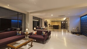 A modern hotel lobby with a sofa set, a coffee table, and a dining area. - Krishna Inn - The Green Hotel (Kolhapur)