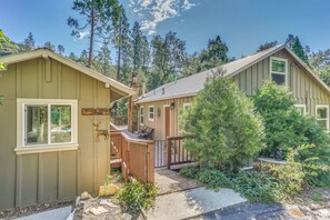 Une cabane dotée d’une terrasse, entourée d’arbres et offrant une vue sur un ciel dégagé.