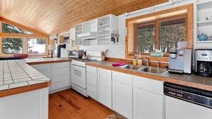 A modern kitchen with white cabinets, a wooden countertop, and a large window. - Fish, float, or raft out of your front door, MT's wilderness at your fingertips! (Bonner)