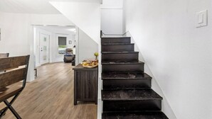Eine Treppe mit dunkler Holzvertäfelung, eine hölzerne Bank und ein kleiner Tisch mit einer Obstschale.