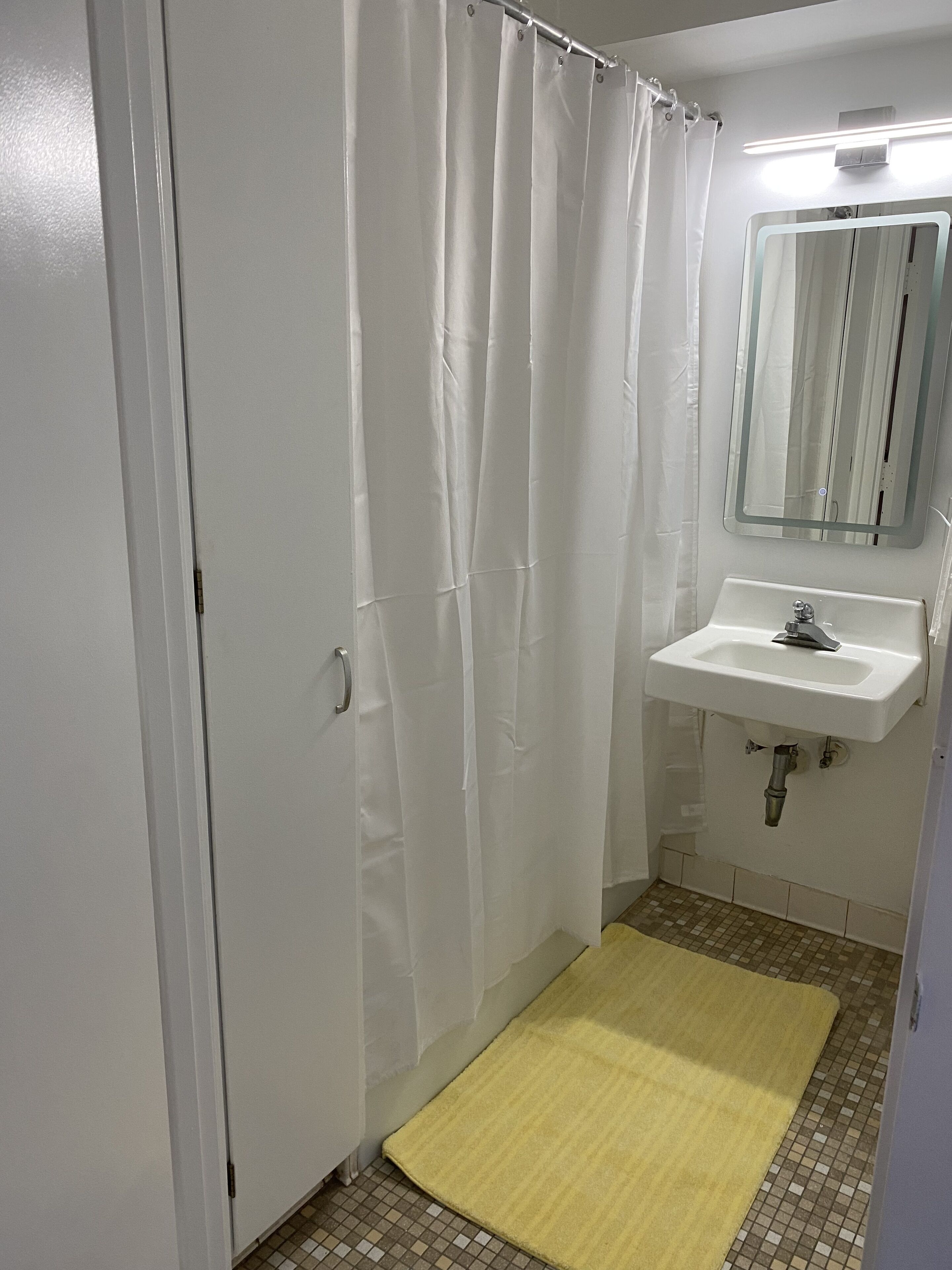A bathroom with a shower curtain, a sink, and a mirror.