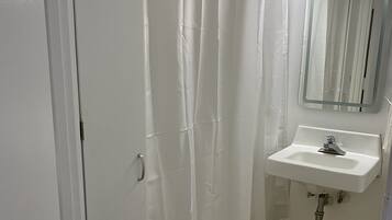 A bathroom with a shower curtain, a sink, and a mirror.