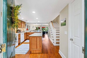 A kitchen with wooden cabinets, a marble island, and a view to the living area.