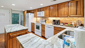 Una cocina con armarios de madera, un refrigerador blanco, un microondas, una estufa y un lavamanos.
