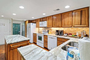 Una cocina con armarios de madera, un refrigerador blanco, un microondas, una estufa y un lavamanos.