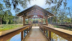 A wooden bridge leading to a covered pavilion with a view of a body of water and trees. - 3 Story Condo - Bonus Room Upstairs! (Hilton Head Island)