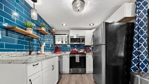 Una cocina moderna con salpicadero de azulejos azules, electrodomésticos de acero inoxidable y estanterías de madera.