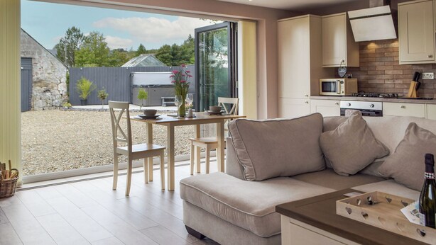 A modern kitchen with a dining area, a sofa, and a view of the outside. - 1 bedroom accommodation in Llanteg (Llanteg)