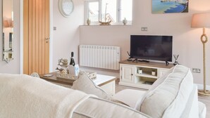 A living room with a sofa, a television, a window with a view, a clock, and a door. - 1 bedroom accommodation in Llanteg (Llanteg)