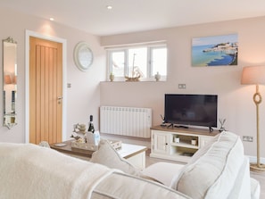 A living room with a sofa, a television, a window with a view, a clock, and a door. - 1 bedroom accommodation in Llanteg (Llanteg)