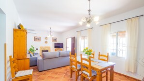 Ein Wohnzimmer mit einer Couch, einem Holzesstisch, Stühlen und einem Fernseher.
