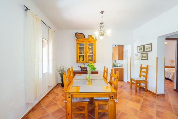 A dining area with a wooden table and chairs, a cabinet with glass doors, and a chandelier.