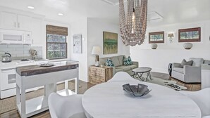 Una cocina moderna con armarios blancos, una isla de madera y una lámpara colgante.