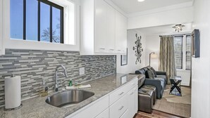 A modern kitchen with a large window, white cabinets, and a tiled backsplash.