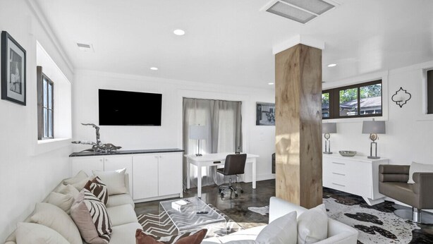 A modern living room with a sofa, coffee table, and a large wooden column.