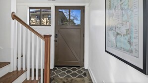 A staircase with wooden steps and white railings leading to a brown door with a window.