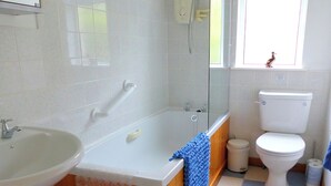 Kylpyhuone, jossa on pesuallas, kylpyamme ja wc, ja jonka lattialla on ruutukuvio.