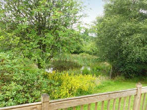Ein Holzzaun mit üppigem Grün und gelben Blüten im Hintergrund.