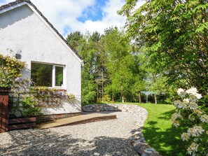 A white house with a stone pathway leading to a wooden deck. - Bo Nan Taigh Cottage (Aberfoyle)
