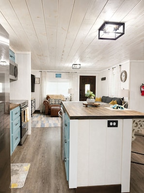 Une cuisine dotée d’un îlot central, d’un plancher en bois et d’un plafond avec des poutres apparentes.
