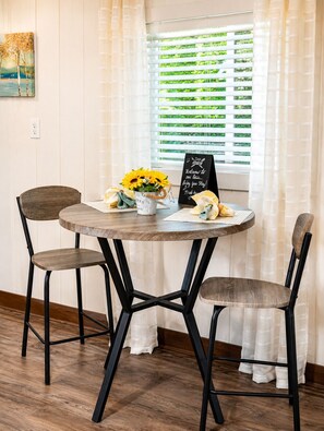 A round wooden table with two chairs, a bucket of sunflowers, and a welcome sign. - Escape to the Smokies! Tiny House Cabin-Special - 4 Night Min w/free cleaning! (Gatlinburg)