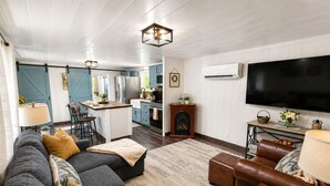 Una sala moderna con un sofá modular, un sillón de cuero y una televisión.