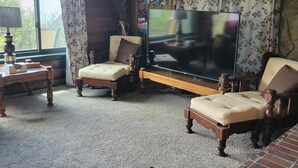 A living room with a television, two armchairs, a coffee table, and a fireplace. - Hot tub fun,  warm up by the fire pit, after a long day of all day play!  (Collbran)