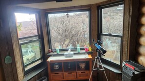 A room with large windows, a telescope, and a speaker on a wooden shelf. - Hot tub fun,  warm up by the fire pit, after a long day of all day play!  (Collbran)