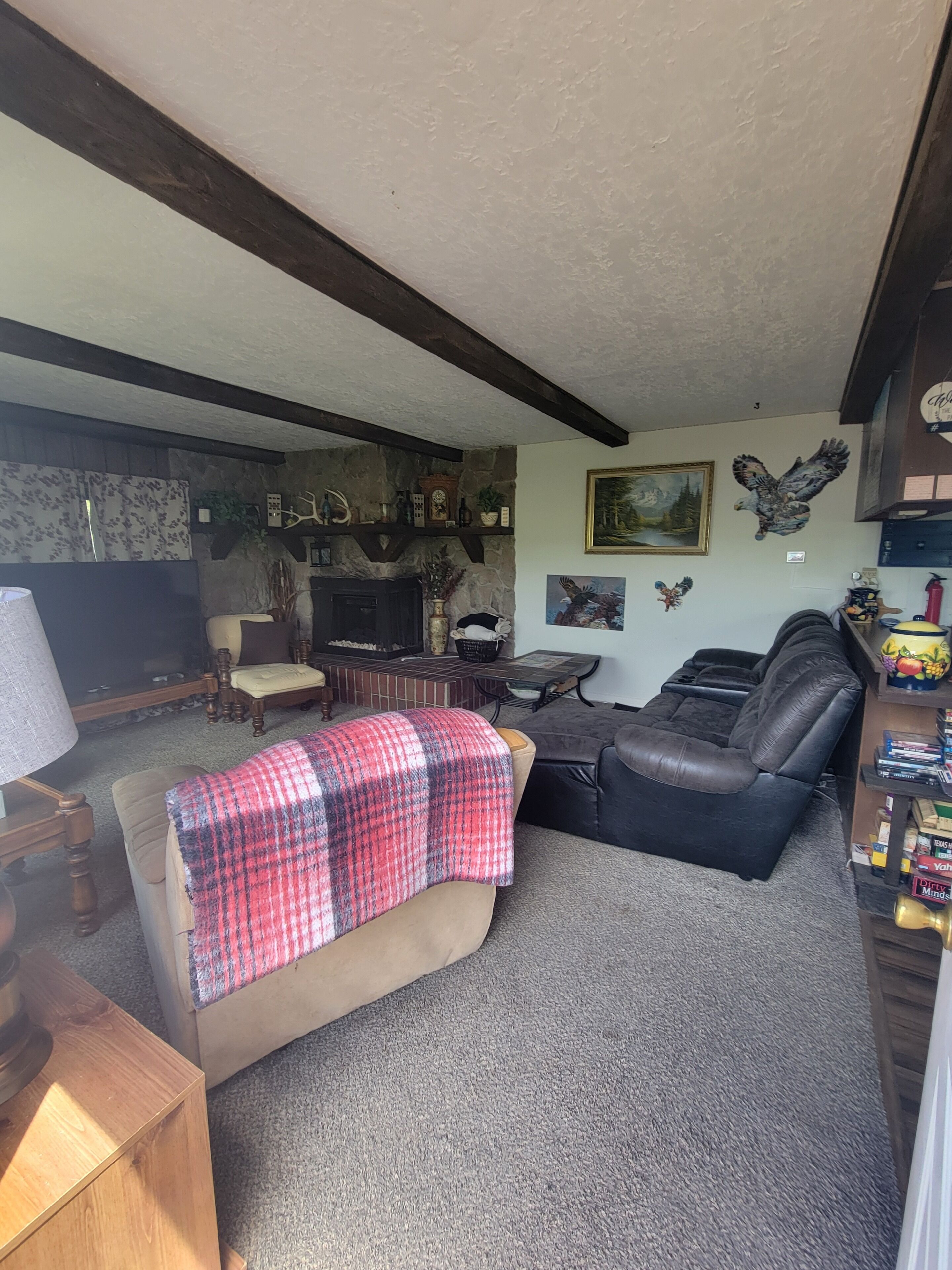 A cozy living room with a fireplace, leather sofa, and various wall decorations.