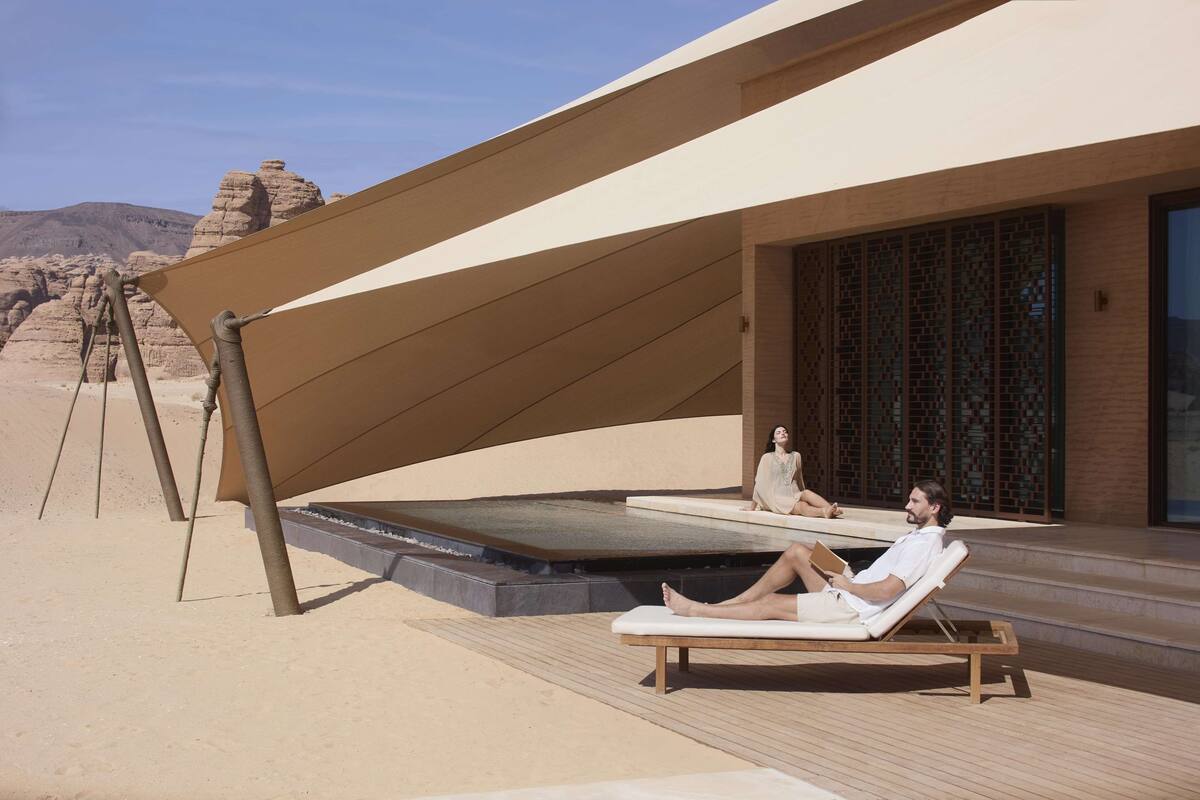 A desert resort with a pool, lounge chairs, and a shaded area.