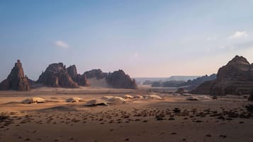 Experience the vast desert landscape with scattered tent accommodations amidst unique rock formations.