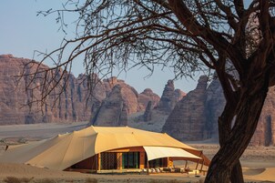 Tienda de campaña en el desierto con vistas a formaciones rocosas.
