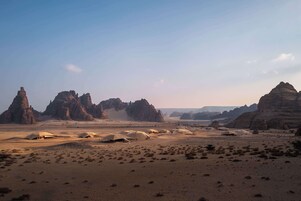 Paisaje desértico con varias tiendas de campaña y formaciones rocosas.