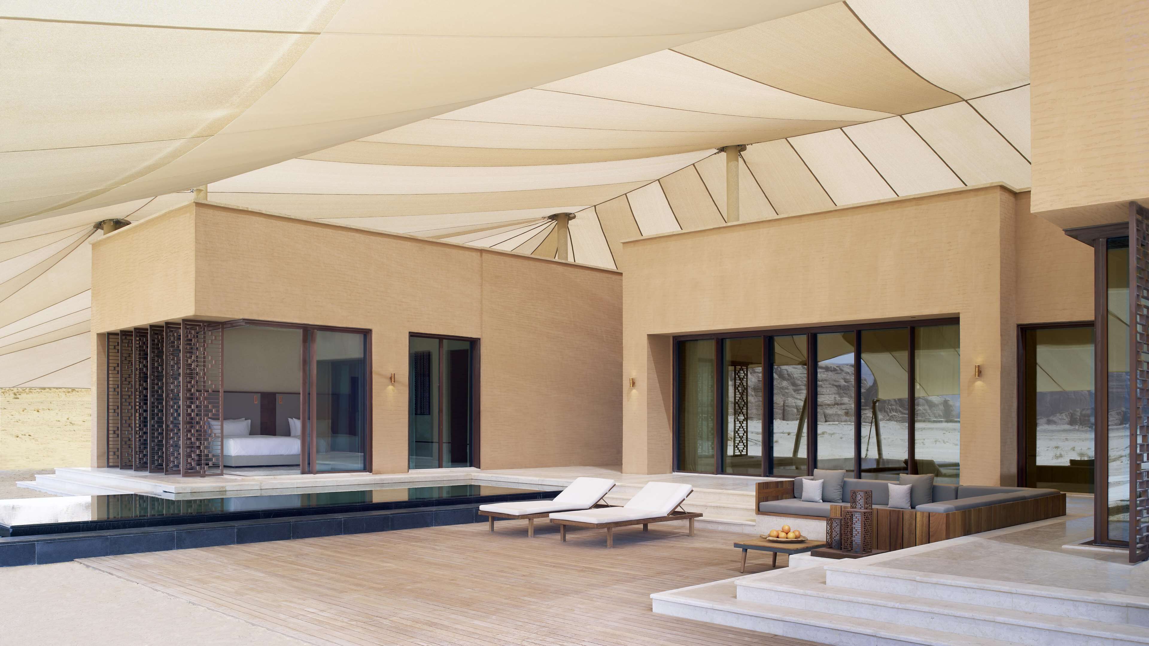 Un área de piscina moderna al aire libre con sillones reclinables, un espacio para sentarse y vistas del paisaje circundante.