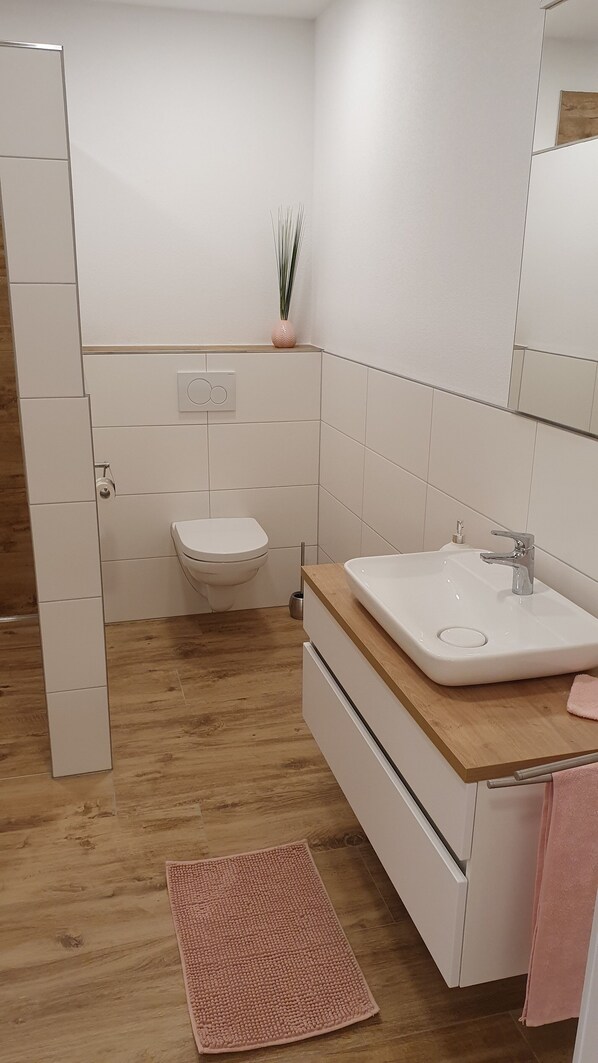 Un baño moderno con inodoro, lavabo y espejo.