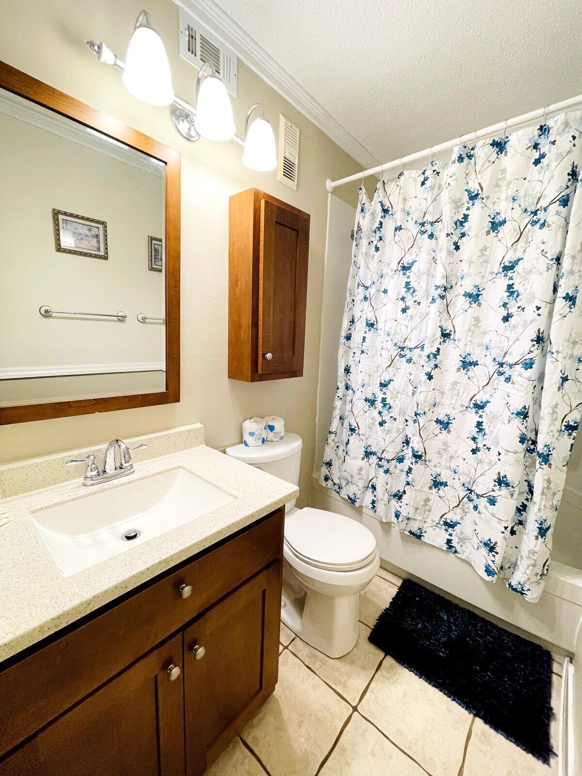 A bathroom with a sink, mirror, toilet, and shower curtain.