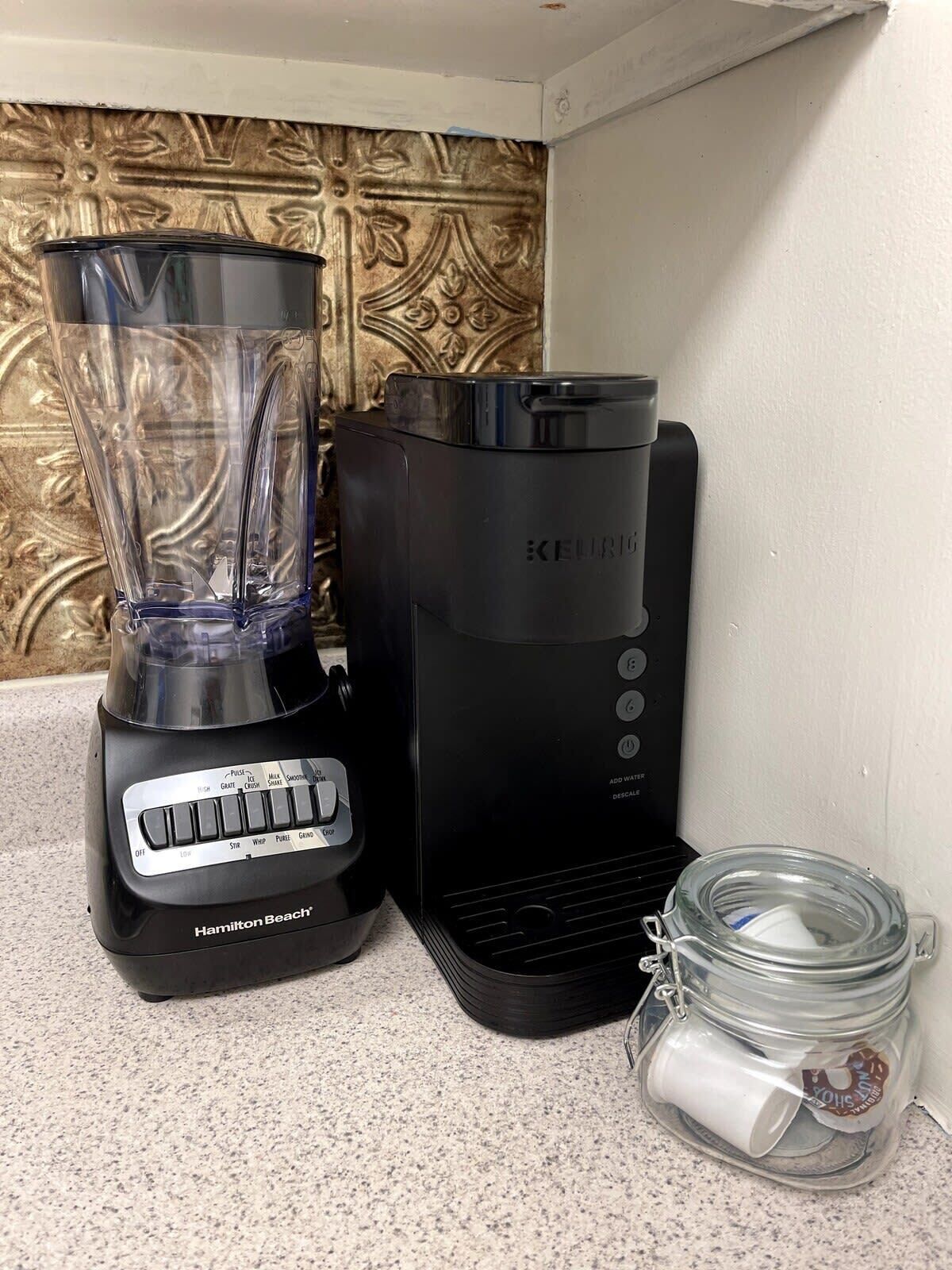 Una licuadora y cafetera Hamilton Beach sobre una encimera de cocina con un salpicadero decorativo.