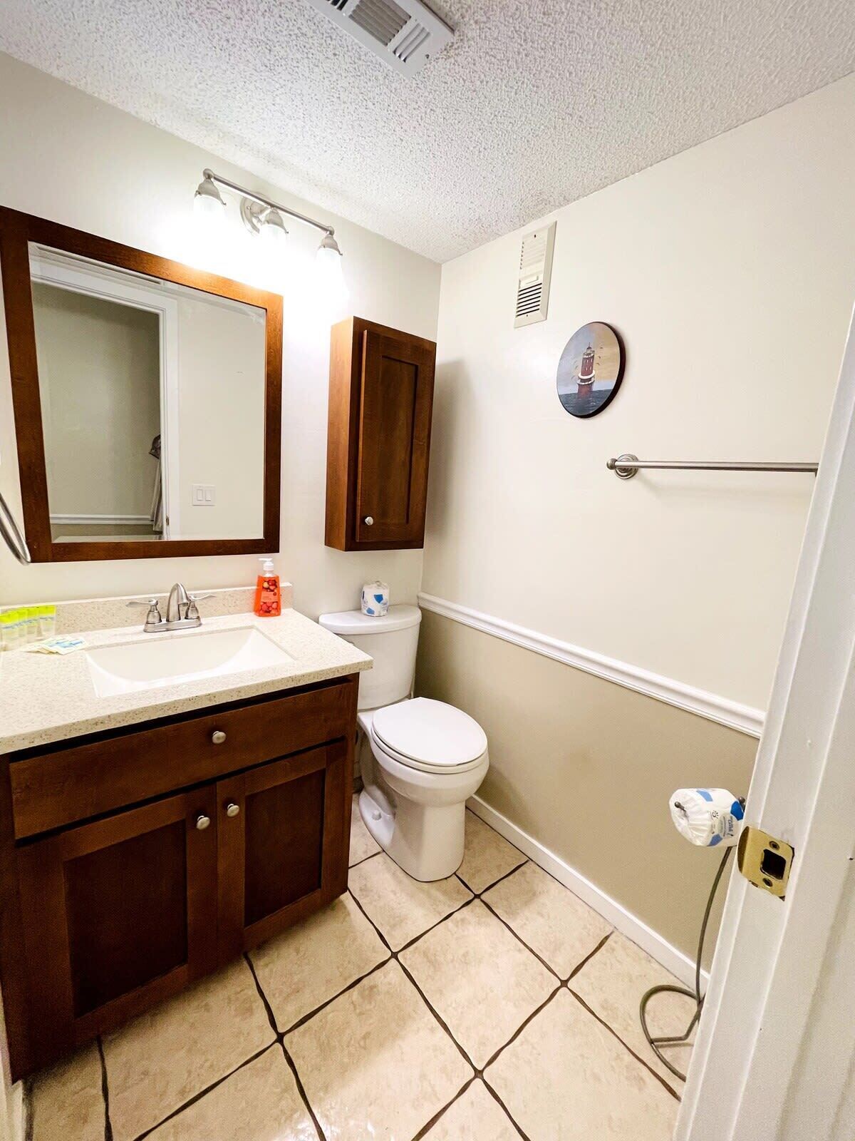 Une salle de bain équipée d’un lavabo, d’un miroir, de toilettes et d’un porte-serviettes.