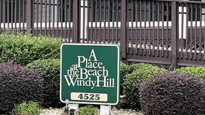 Ein grünes Schild mit weißer Schrift, das "A Place at the Beach Windy Hill" und die Nummer 4525 zeigt.