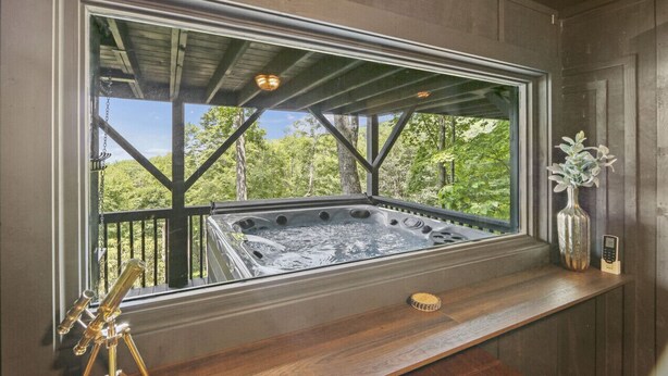 Een bubbelbad met een houten terras en uitzicht op het bos.
