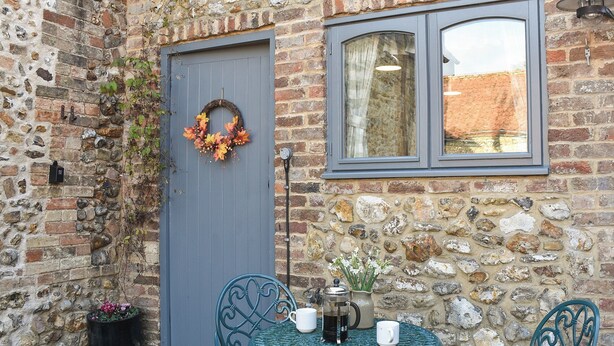 A stone building with a blue door, a window, and a table with chairs. - The Old Butcher's Shop (Wereham, near King&rsquo;s Lynn)