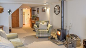 A cozy living room with a plaid armchair, a sofa, a fireplace, and a clock on the wall. - The Old Butcher's Shop (Wereham, near King&rsquo;s Lynn)