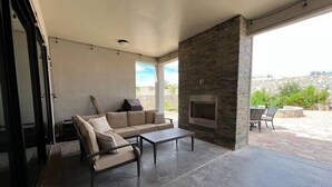 An outdoor living area with a stone fireplace, a sofa, and a table. - Purple Sage Garden Retreat (Las Cruces)