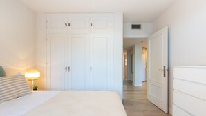 Un dormitori amb un llit, una nitzeta amb una làmpada i un armari.