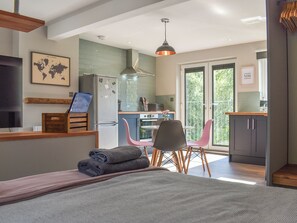 A modern kitchen with a refrigerator, stove, and dining area with chairs.